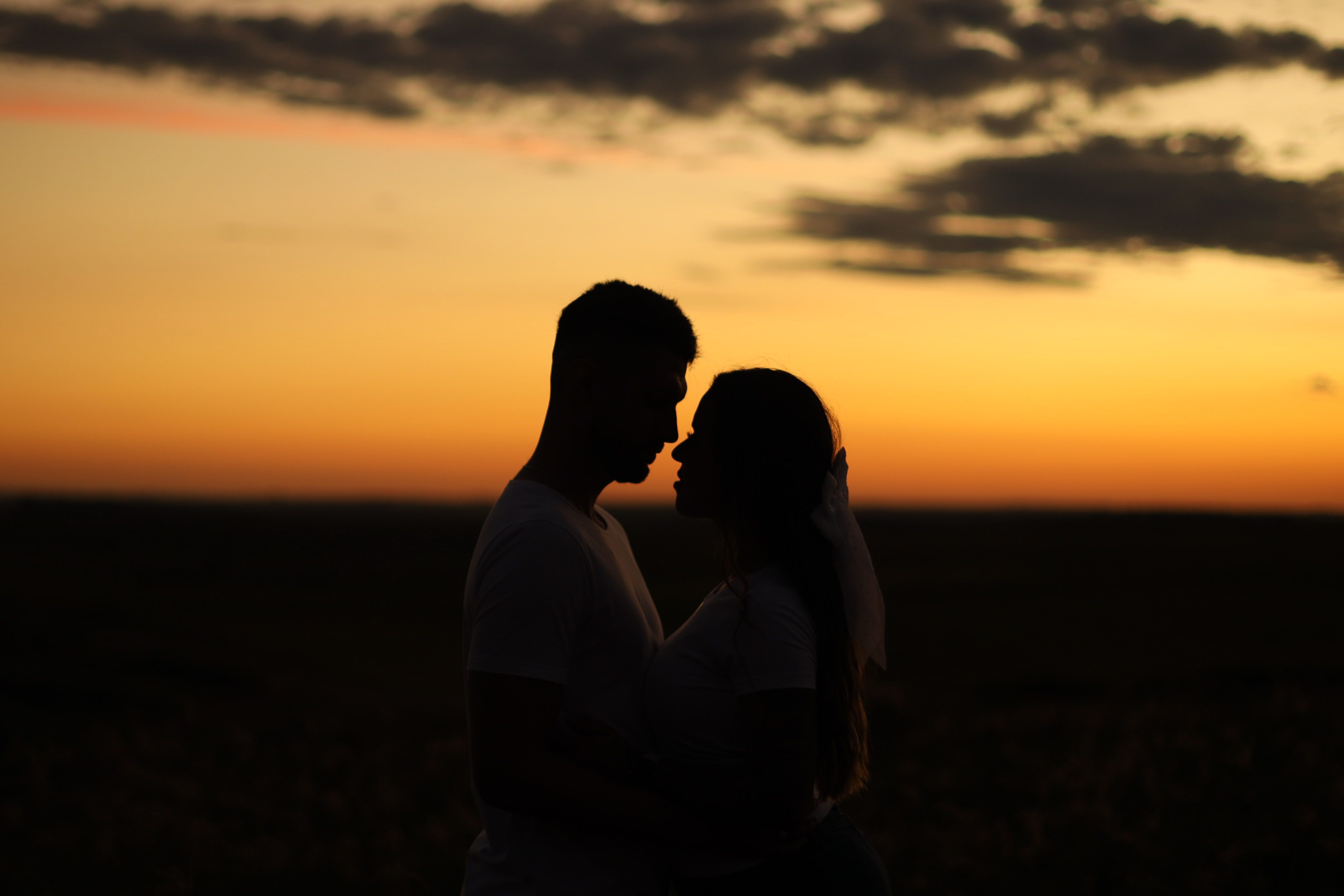 silueta de una pareja heterosexual a punto de besarse al atardecer